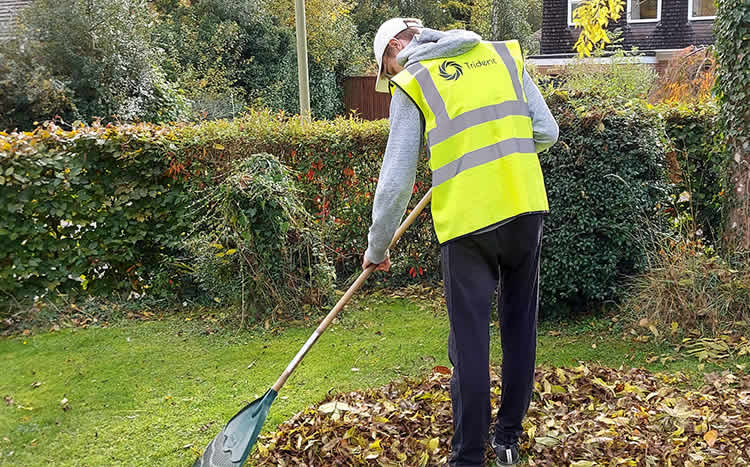 A member of the trident team raking leaves in supporting environmental management